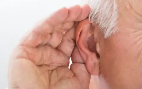 Mano di anziano che copre l'orecchio, forse per sentire meglio o per proteggersi da allucinazioni uditive.