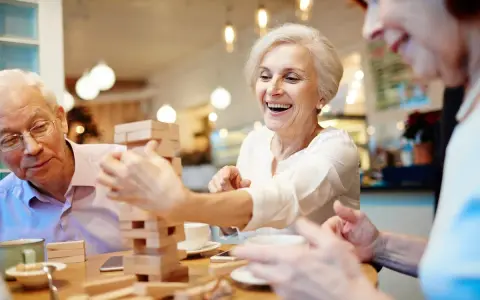 Anziani sorridono giocando a Jenga, un'attività stimolante per anziani con demenza.
