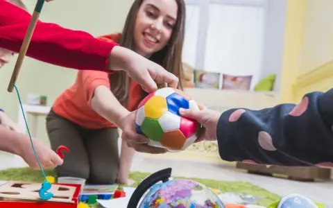 Bambini e terapista giocano con una palla colorata, un globo e un gioco di incastri. La terapia occupazionale cos'è? È questo: gioco e apprendimento.
