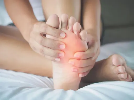 Mani che massaggiano la pianta del piede, evidenziando un'area arrossata. Potrebbe essere utile per chi soffre di metatarsalgia esercizi mirati.