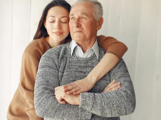 Un abbraccio affettuoso: un modo per come calmare una persona con demenza senile. La giovane donna stringe dolcemente l'anziano uomo, offrendo conforto e sicurezza.