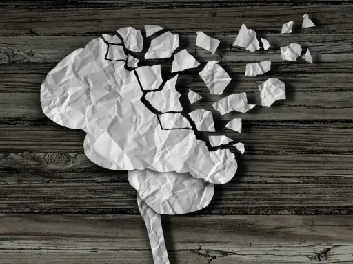 Cervello di carta sgretolato, simbolo dei vuoti di memoria negli anziani. Frammenti che si staccano, come ricordi perduti.