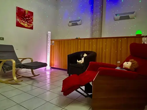 Una stanza snoezelen accogliente con sedie comode, luci soffuse e un'atmosfera rilassante.