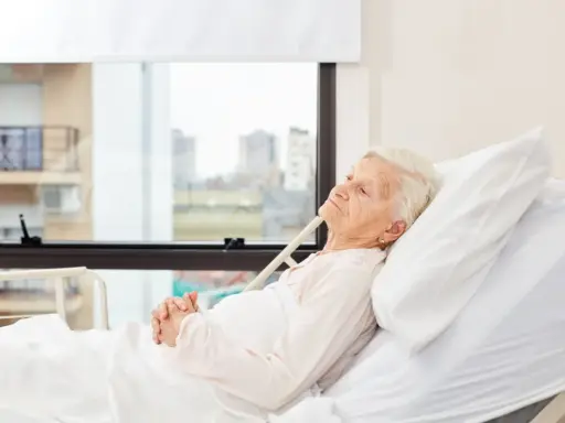 Anziana allettata in ospedale, con mani giunte. La domanda "quanto può vivere un anziano allettato" è complessa e dipende da molti fattori.