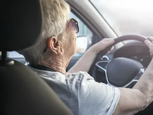 Anziana al volante, con mani sul volante, potrebbe suggerire il tema del decadimento cognitivo nell'anziano e la sua autonomia.