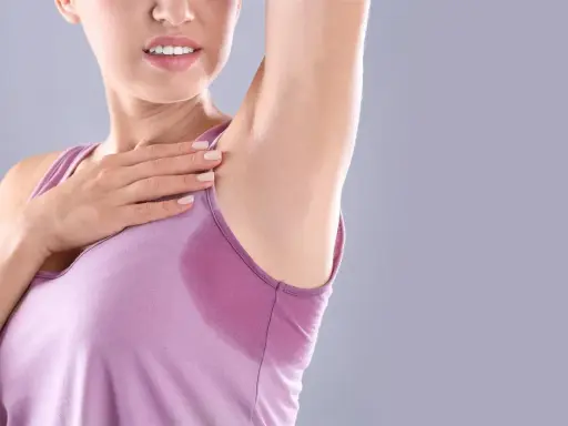 Donna con ascella bagnata, un segno di sudorazione eccessiva. Le cause possono essere molteplici, dallo stress al caldo.