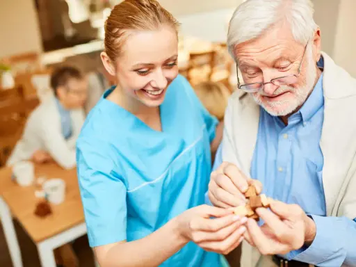 Assistente sorridente aiuta un anziano con demenza a completare un puzzle, mostrando come le fissazioni possano essere gestite con pazienza e attività stimolanti.
