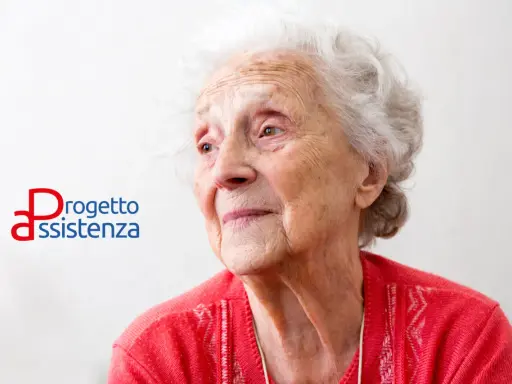 Ritratto di un'anziana signora con capelli bianchi, che guarda lontano. Accanto, il logo "Progetto Assistenza", che evoca cura e supporto, anche in caso di demenza senile a 88 anni.