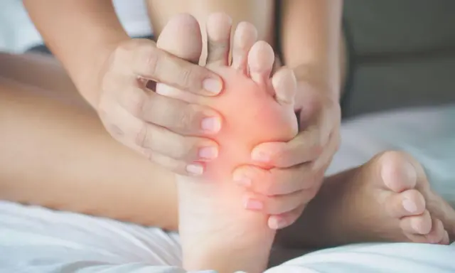 Mani che massaggiano la pianta del piede, evidenziando un'area arrossata. Potrebbe essere utile per chi soffre di metatarsalgia esercizi mirati.