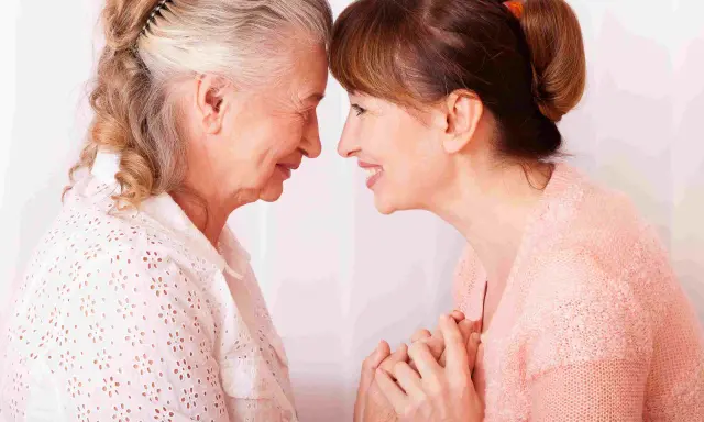 Un abbraccio tra madre e figlia, un momento di affetto che può aiutare a gestire i sintomas de alzheimer, con mani che si stringono.