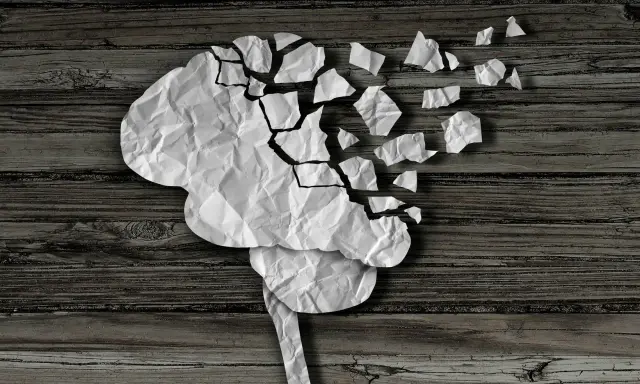Cervello di carta sgretolato, simbolo dei vuoti di memoria negli anziani. Frammenti che si staccano, come ricordi perduti.