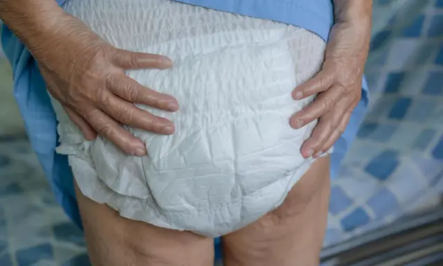 Mani anziane che sistemano un doppio pannolone per garantire il massimo comfort e protezione.