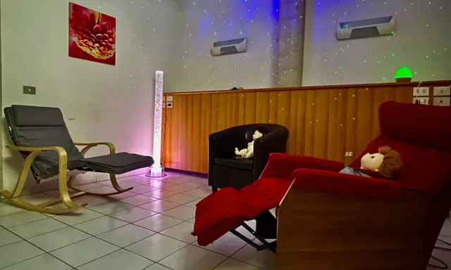 Una stanza snoezelen accogliente con sedie comode, luci soffuse e un'atmosfera rilassante.