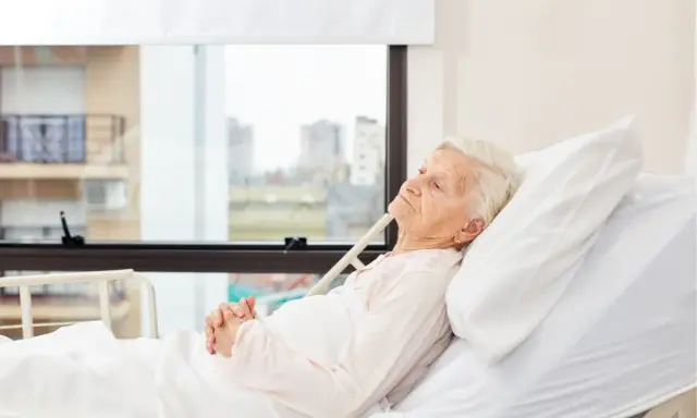 Anziana allettata in ospedale, con mani giunte. La domanda "quanto può vivere un anziano allettato" è complessa e dipende da molti fattori.