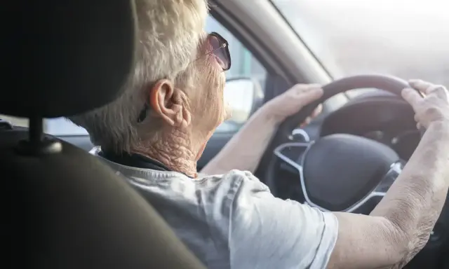 Anziana al volante, con mani sul volante, potrebbe suggerire il tema del decadimento cognitivo nell'anziano e la sua autonomia.