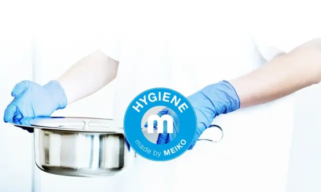 Mani guantate presentano una padella metallica, pronta per essere usata. Il logo MEIKO sottolinea l'igiene.