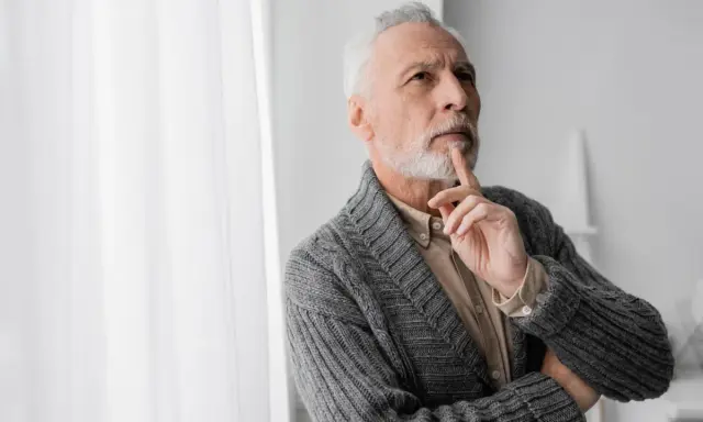 Uomo anziano con barba bianca, pensieroso, con un dito sul mento, forse valutando i risultati di un decadimento cognitivo test.