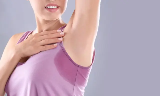 Donna con ascella bagnata, un segno di sudorazione eccessiva. Le cause possono essere molteplici, dallo stress al caldo.