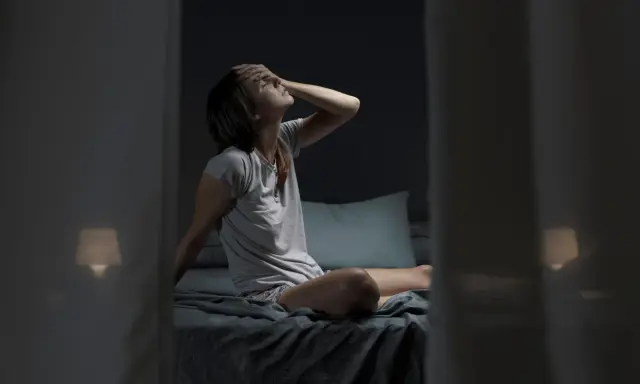 Donna a letto, con la mano sulla fronte, soffre il caldo notturno. Forse il cortisone fa sudare di notte.