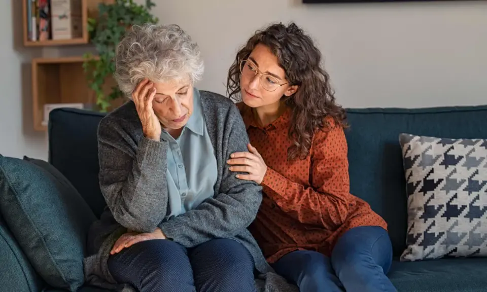 Una giovane donna conforta un'anziana con Alzheimer, mostrando quando ricoverare un malato di Alzheimer.