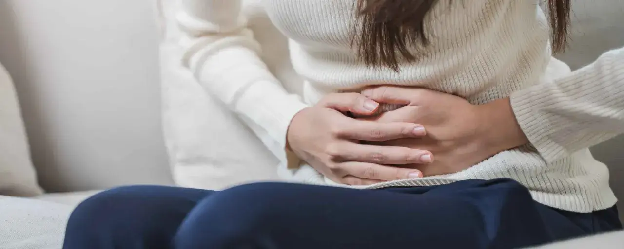 Mani che stringono l'addome, forse per dolori o crampi. Le feci verdi potrebbero essere un sintomo.