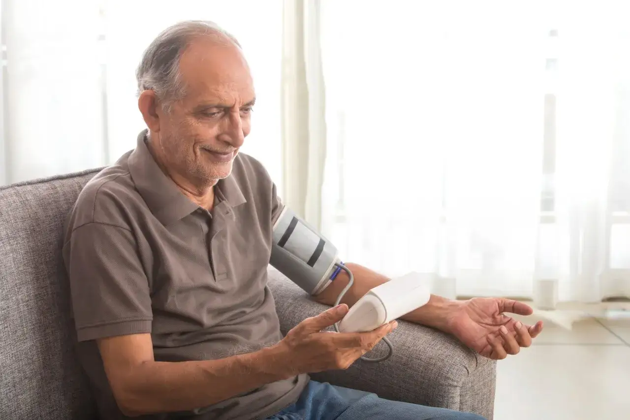 Un anziano di 90 anni controlla la sua pressione bassa con un misuratore.