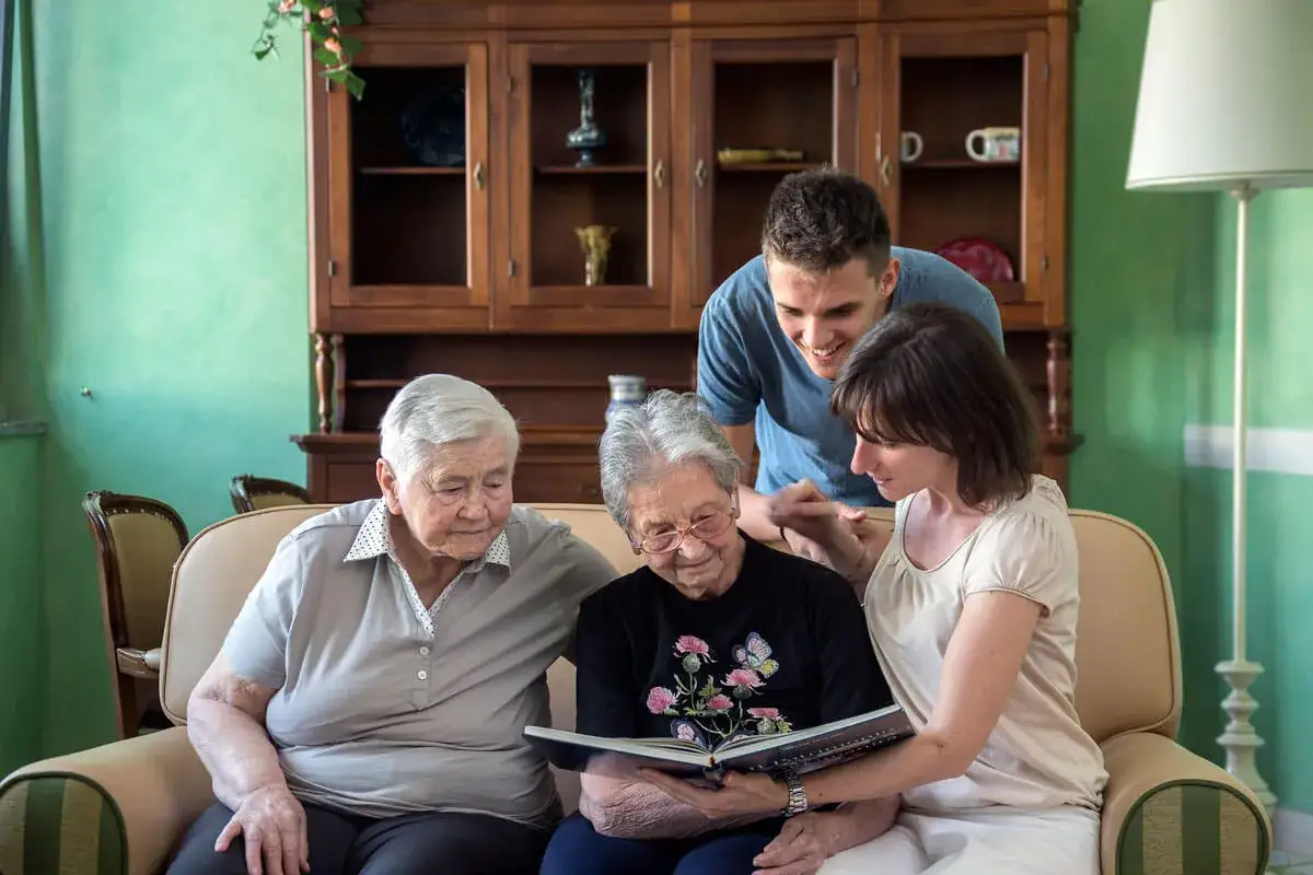 Famiglia riunita attorno a un album di foto. Una donna, forse malata di Alzheimer, guarda con affetto i ricordi con i suoi cari.