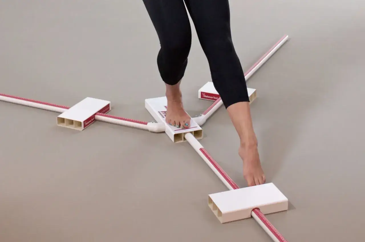 Piedi nudi su un dispositivo a stella per un balance test. Le gambe indossano leggings neri.