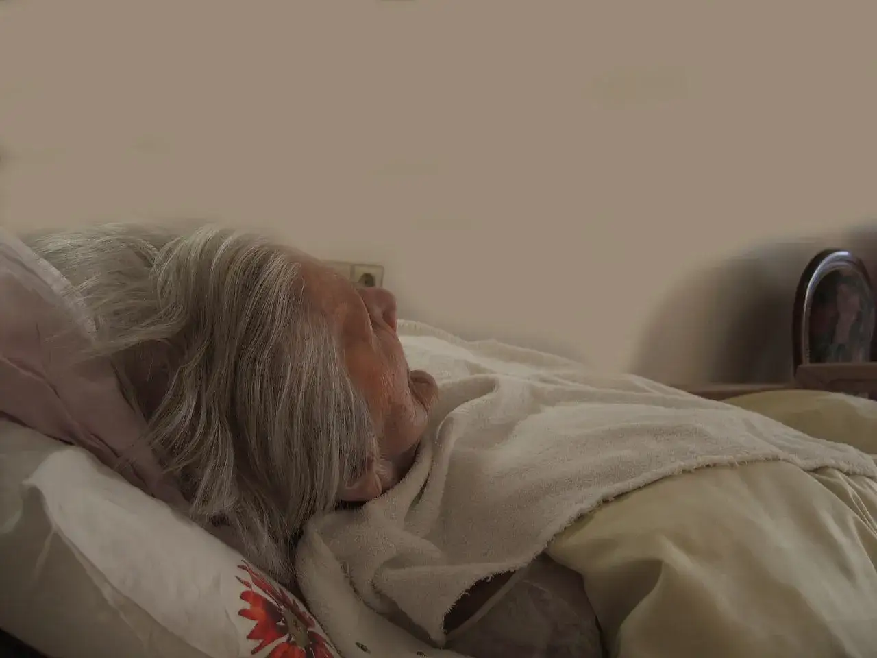 Anziano dorme, capelli grigi coprono il viso. La demenza può portare a fissazioni, ma qui c'è solo riposo.