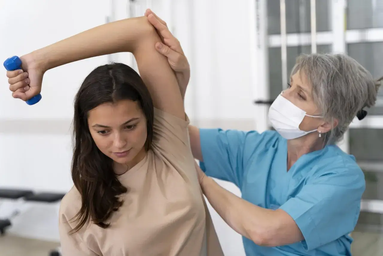 Fisioterapista assiste paziente con protesi inversa spalla in riabilitazione, sollevando un piccolo peso.