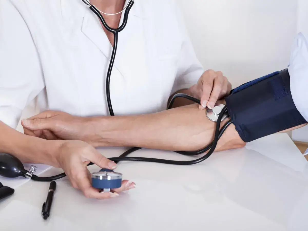 Medico misura la pressione: 97 67. Il bracciale è gonfiato, lo stetoscopio posizionato.