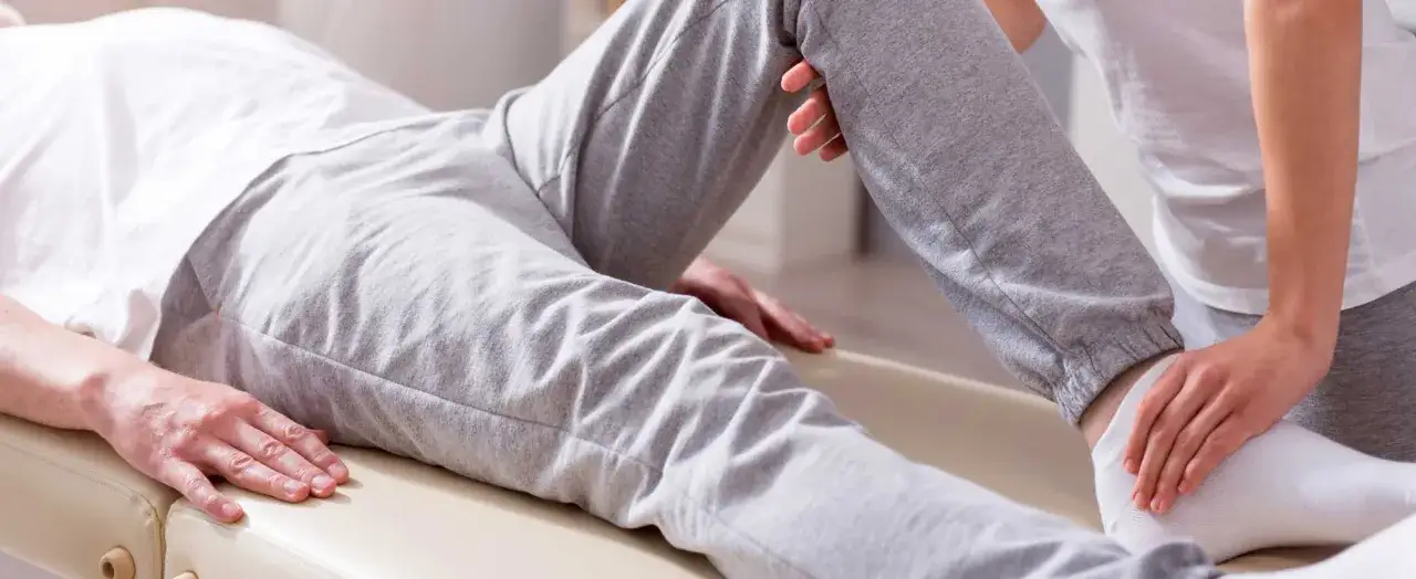 Fisioterapista assiste un paziente con potenziale perdita muscolare alle gambe, eseguendo un esame.