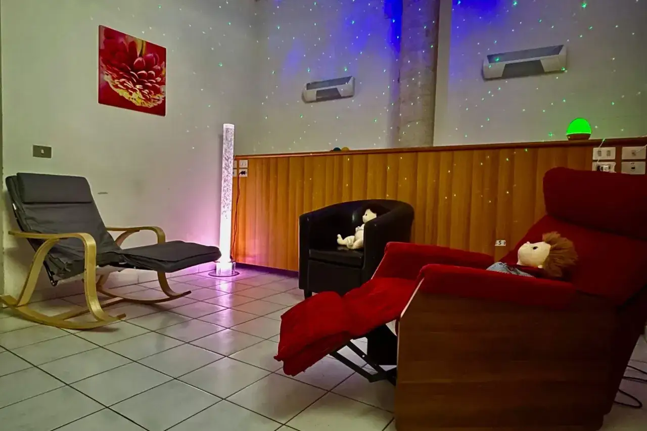 Una stanza snoezelen accogliente con sedie comode, luci soffuse e un'atmosfera rilassante.