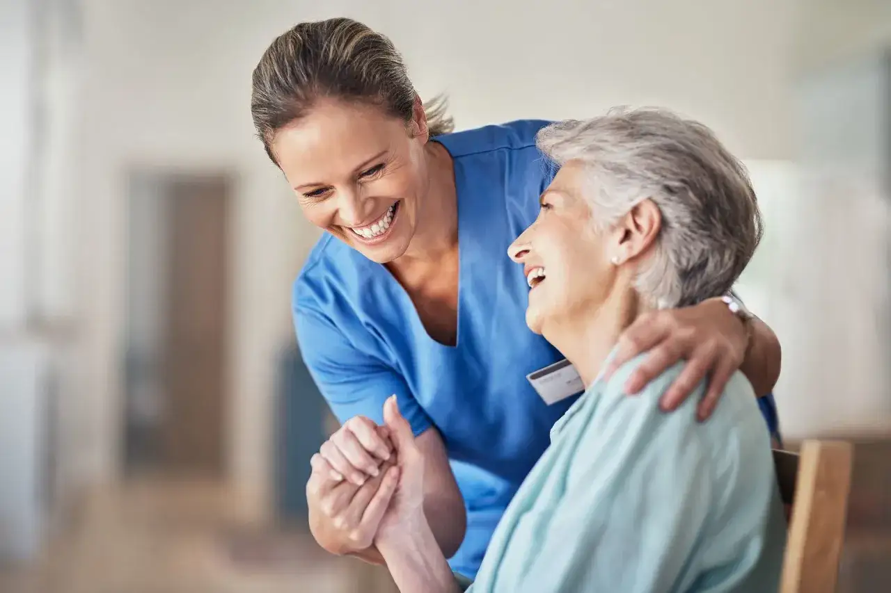 Un sorriso e una mano che stringe l'altra: un abbraccio che mostra il socio sanitario che lavoro puoi fare, offrendo cura e compagnia.