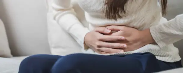 Mani che stringono l'addome, forse per dolori o crampi. Le feci verdi potrebbero essere un sintomo.