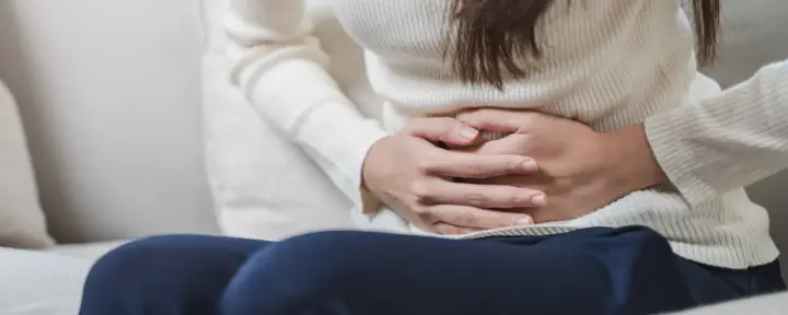 Mani che stringono l'addome, forse per dolori o crampi. Le feci verdi potrebbero essere un sintomo.